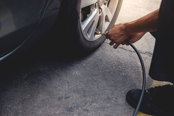 Man filling Air into the Tire. Car Driver Checking Air Pressure and Maintenance his Car by himself before Traveling © blacksalmon
