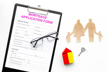 Mortgage concept. Mortgage application form near key and house made of constructor, family cutout on white background top view