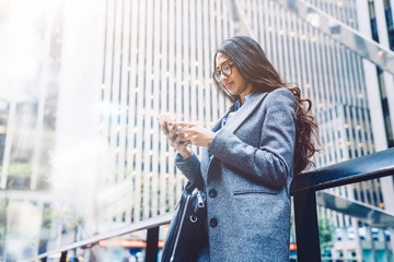 30 years old businesswoman standing outdoors in downtown while using mobile phone during work...