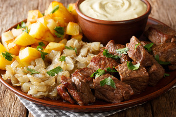 Beef Rydberg with stewed onions and fried potatoes with mustard sauce close-up on a plate. horizontal, rustic