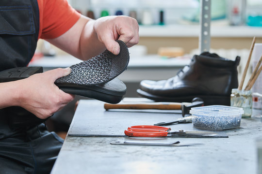 Shoemaker repair shoe. Glueing the sole for male footwear