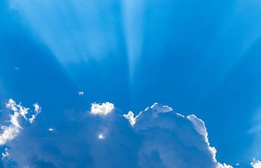 Blue sky and white clouds blue sky on a bright day with white clouds coming in floating come to cover sun causes a white beam causing beauty in the sky.
