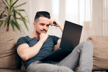 Man Sitting on a Couch Using His Laptop