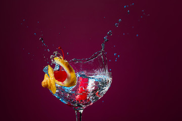 Colorful cocktail in glass with splashes garnished with lemon and cherries.