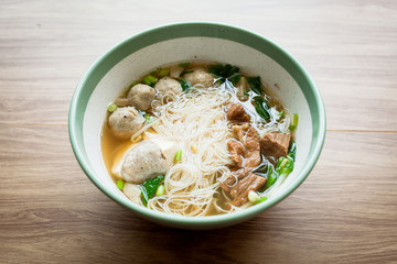 Soup and noodle with pork meatball and boil pork with vegetable serve with big bowl on the wood table 