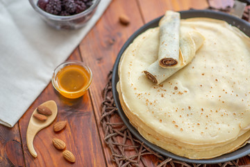 A stack of homemade pancakes on a frying pan, brown background
