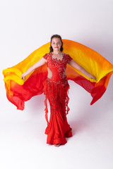 Young girl with shawl and in red dress performs oriental dance on white background