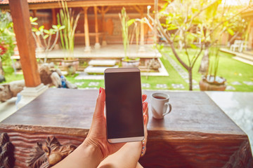 Woman using cellphone in a tropical backyard.