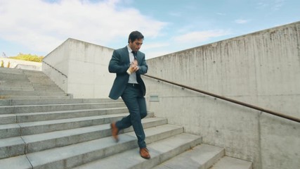 Cheerful and Happy Businessman in a Suit is Holding Coffee and Actively Dancing While Walking Down the Stairs