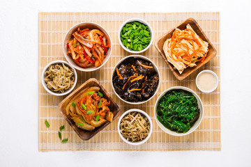 selection of Korean Asian food in bowls on bamboo mat
