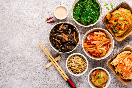 Assorted korean pickled food and chopsticks on gray background