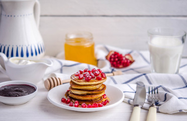 Pancakes with pomegranate seeds, honey and powdered sugar