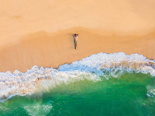 The guy lies on a sandy beach on a tropical island. Drone view