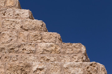 Fototapeta na wymiar stone wall with steps against blue sky