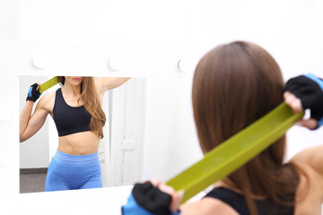 Fitness z gumami.  Kobieta trenuje przed lustrem.