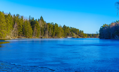 A nice image of a partly ice-covered forest lake on a February day in Tyresta National Park, Sweden