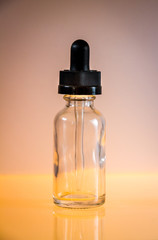 Glass dropper bottle on orange background