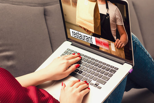 Ordering food online concept: woman with a laptop showing fast food website on screen. Screen graphics are made up. - Powered by Adobe