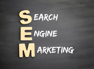Obraz premium Wooden alphabets building the word SEM - Search Engine Marketing acronym on blackboard