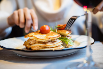 Young woman having breakfast and cut pancakes