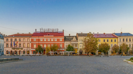 Fototapeta na wymiar Cluj-Napoca city center. View from the Unirii Square to the Josika Palace, Rhedey Palace and Wass Palace at sunrise on a beautiful, clear sky day