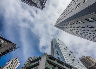 Looking up to the sky in Hong Kong. The tall buildings can not be avoided and can be seen everywhere. Looking up straight up creates an abstract picture of the often glass office buildings. - 250793520