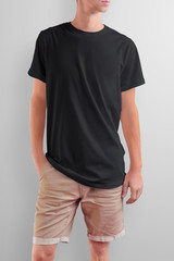 Obraz premium Young slim caucasian man in a black T-shirt on a white studio background.