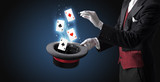 Magician with white gloves conjuring playing cards from a cylinder with magic wand