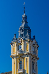 Fototapeta na wymiar Cluj-Napoca City Hall on a sunny summer day with blue sky in Romania. It features a Viennese baroque facade with a corner clock tower