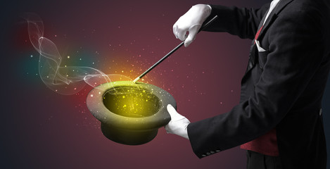 Illusionist hand starts to conjure with white glove and magic wand © ra2 studio