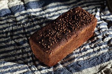Loaf of traditional russian dark bread on rye sourdough with coriander called Borodinsky on a wooden table with linen towel. Healthy food concept. Free space for input text.