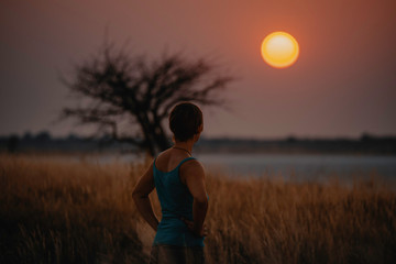 Frau schaut in den Sonnenuntegang bei Baines Baobabs, Nxai Pans National Park, Botswana