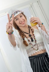 pretty young woman with a summer hat drinks glass of orange juic