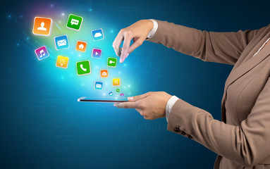 Hand holding tablet and application icons falling inwards
