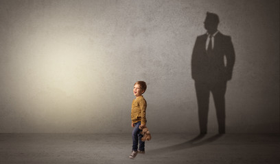 Little boy imagine that he will be businessman and illustrating his future in a big shadow
