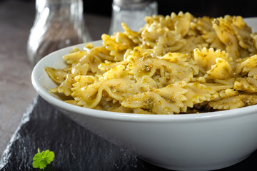 Farfalle pasta with pesto sauce in a white bowl