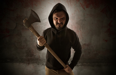 Armed rude assassin in an empty bloody room concept with gun ax chainsaw mallet wrench
