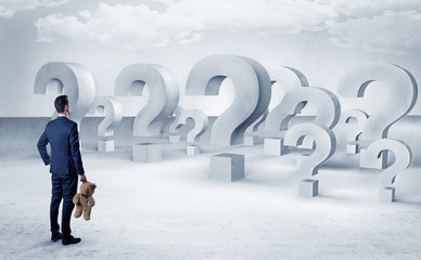 Obraz premium Businessman standing and looking to a bunch of question mark signs 