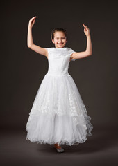Fototapeta na wymiar little girl is dressed in a white ball gown, dark background