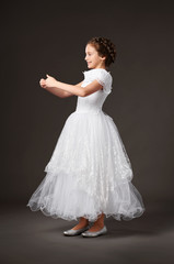 Fototapeta premium little girl is dressed in a white ball gown, dark background