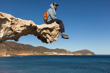 Young man sitting on sculpted rock structure, Los Escullos, Spain