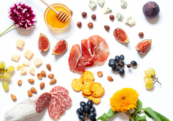 Antipasti food white flat lay with nuts, honey, cured meat, salami, cheeses, grapes and figs. Top view snack concept composition