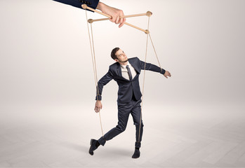 Puppet businessman in an empty room leaded by a huge hand
