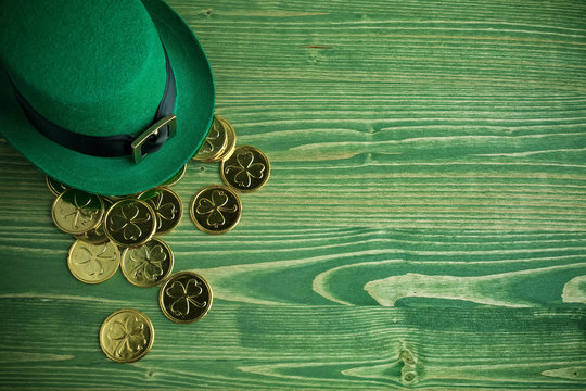 Happy St Patricks Day leprechaun hat with gold coins on vintage green wood background