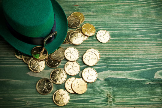 Happy St Patricks Day leprechaun hat with gold coins on vintage green wood background