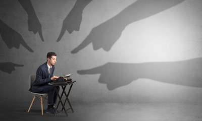 Shadow hand pointing at a small afraid worker
