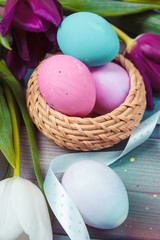 Easter eggs with tulips on blue wooden background