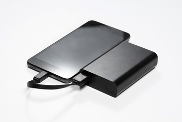 smartphone is charging from the black battery power bank