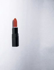 Carrot-colored vertical lipstick lies on a white background open without a cap in a black case 