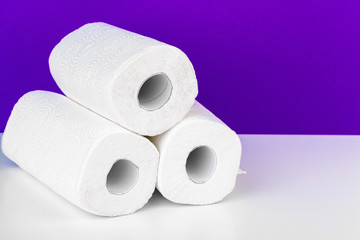 Roll of paper towel on table against purple background